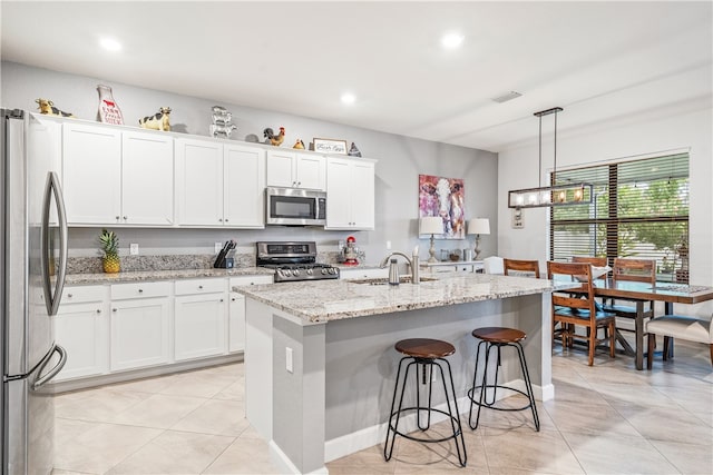 kitchen with stainless steel appliances, white cabinets, and a kitchen island with sink