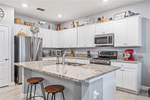 kitchen featuring a kitchen island with sink, appliances with stainless steel finishes, and white cabinetry