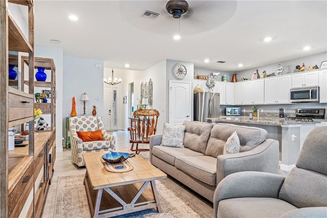 living room with light hardwood / wood-style floors and ceiling fan with notable chandelier