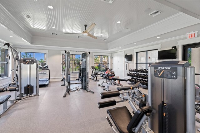 gym featuring ceiling fan, a raised ceiling, and crown molding