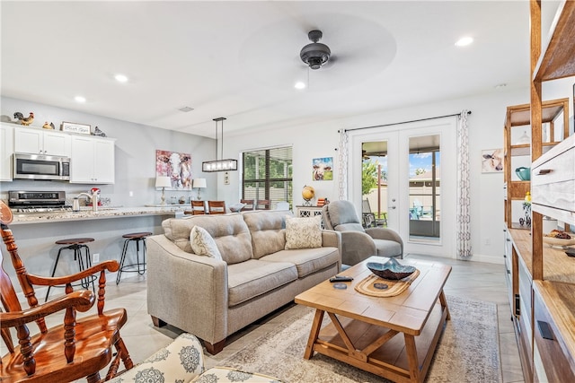 tiled living room with ceiling fan with notable chandelier and french doors