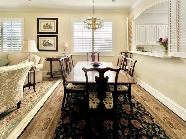 dining area with crown molding, wood-type flooring, and a notable chandelier