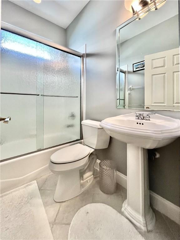 bathroom featuring tile patterned flooring, enclosed tub / shower combo, and toilet