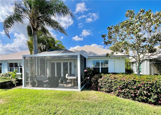 rear view of house with a yard, a sunroom, and a patio area