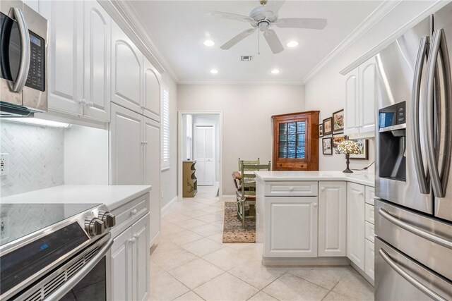 1135 Saint Georges Ln, Vero Beach, FL 32967 - kitchen featuring appliances with stainless steel finishes, a peninsula, light tile patterned floors, light countertops, and white cabinets
