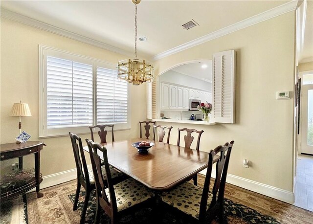 dining area featuring light hardwood / wood-style flooring, ornamental molding, and a chandelier