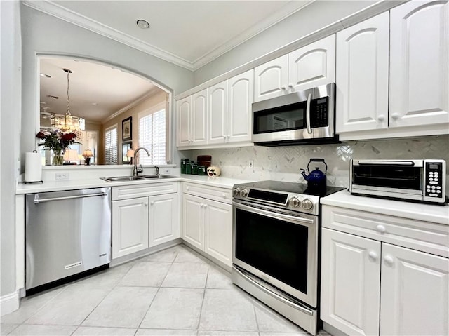 kitchen with sink, crown molding, appliances with stainless steel finishes, white cabinetry, and decorative backsplash