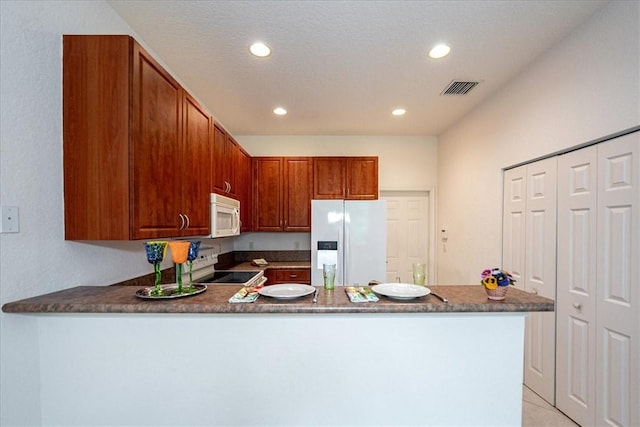 2597 Stockbridge Sq SW Unit 2597, Vero Beach, FL 32962 - kitchen with white appliances, a peninsula, recessed lighting, dark countertops, and light tile patterned floors