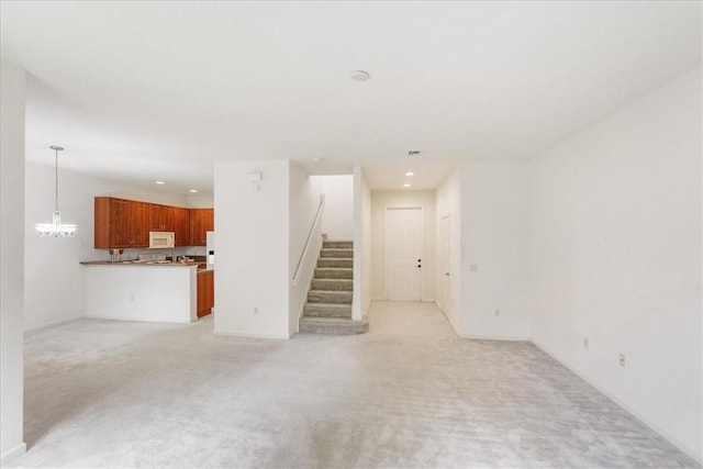 2597 Stockbridge Sq SW Unit 2597, Vero Beach, FL 32962 - unfurnished living room featuring light carpet, stairway, a chandelier, and recessed lighting