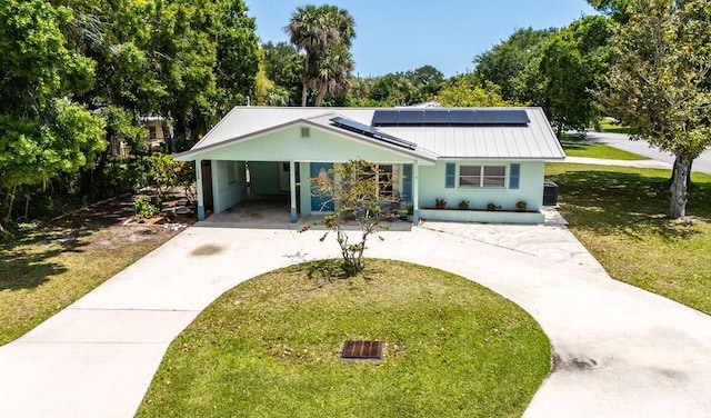 1936 5th Ave, Vero Beach, FL 32960 - ranch-style home with curved driveway, a front lawn, solar panels, and a metal roof
