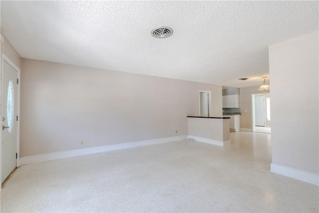1936 5th Ave, Vero Beach, FL 32960 - unfurnished living room featuring a textured ceiling and a chandelier