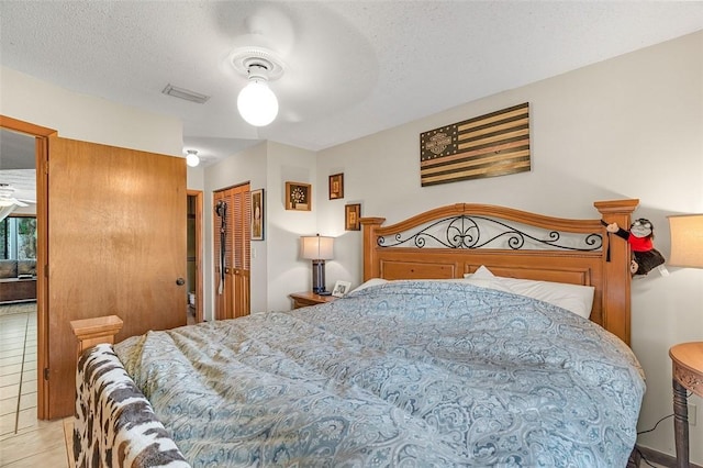 tiled bedroom featuring ceiling fan, a closet, and a textured ceiling