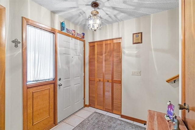 foyer entrance with a chandelier, a textured ceiling, and light tile patterned floors