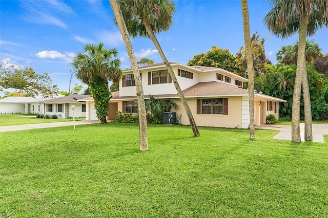 view of front of house with a garage, cooling unit, and a front lawn