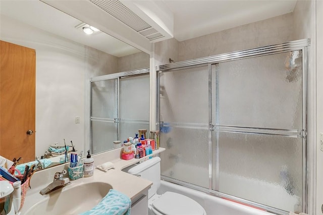 full bathroom with bath / shower combo with glass door, vanity, and toilet