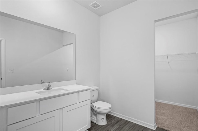 8425 98th Ct, Vero Beach, FL 32967 - bathroom featuring toilet, vanity, a spacious closet, baseboards, and wood finished floors