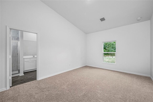 8425 98th Ct, Vero Beach, FL 32967 - unfurnished bedroom with carpet floors, baseboards, ensuite bath, and high vaulted ceiling