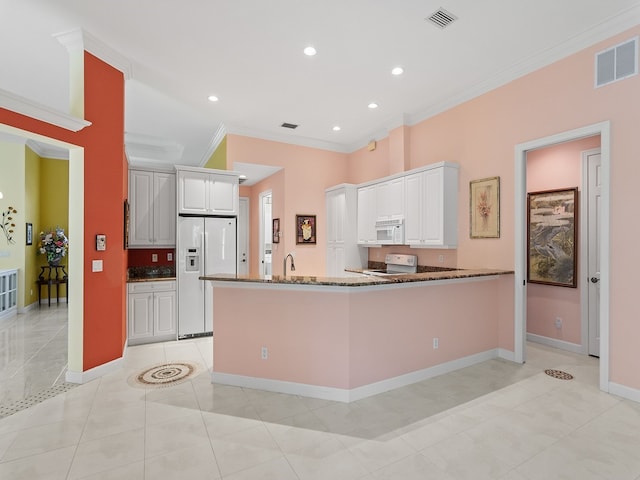 kitchen featuring light tile patterned floors, white appliances, dark stone counters, crown molding, and white cabinets