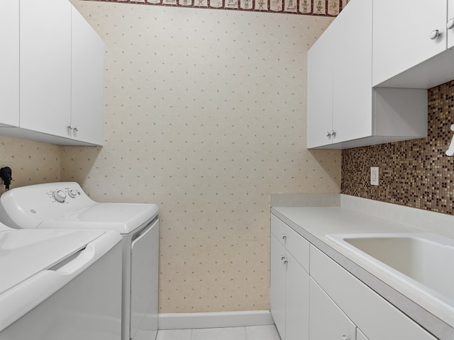 clothes washing area featuring sink, light tile patterned flooring, separate washer and dryer, and cabinets