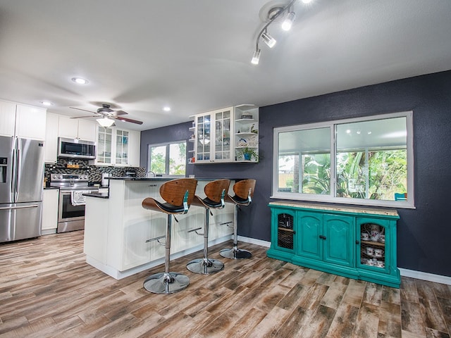 624 24th St SW, Vero Beach, FL 32962 - kitchen featuring stainless steel appliances, wood finished floors, white cabinetry, dark countertops, and glass insert cabinets