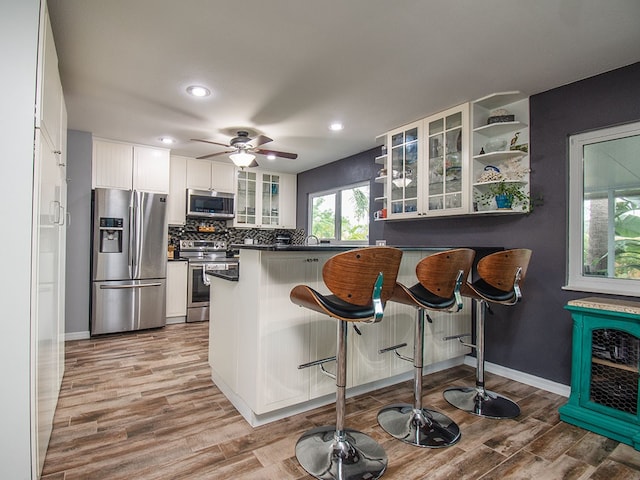 624 24th St SW, Vero Beach, FL 32962 - kitchen featuring appliances with stainless steel finishes, dark countertops, open shelves, a peninsula, and light wood-style flooring