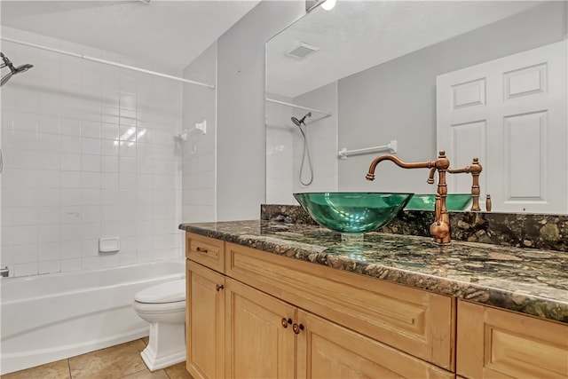 full bathroom with vanity, a textured ceiling, tile patterned flooring, toilet, and tiled shower / bath