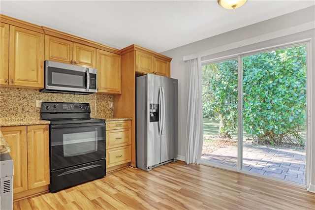 kitchen featuring tasteful backsplash, appliances with stainless steel finishes, light stone counters, and light hardwood / wood-style floors