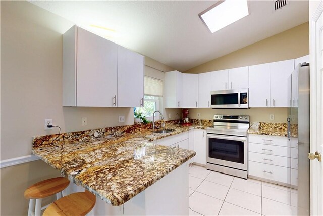 3405 Atlantic Blvd, Vero Beach, FL 32960 - kitchen featuring stainless steel appliances, a sink, a peninsula, light stone countertops, and vaulted ceiling