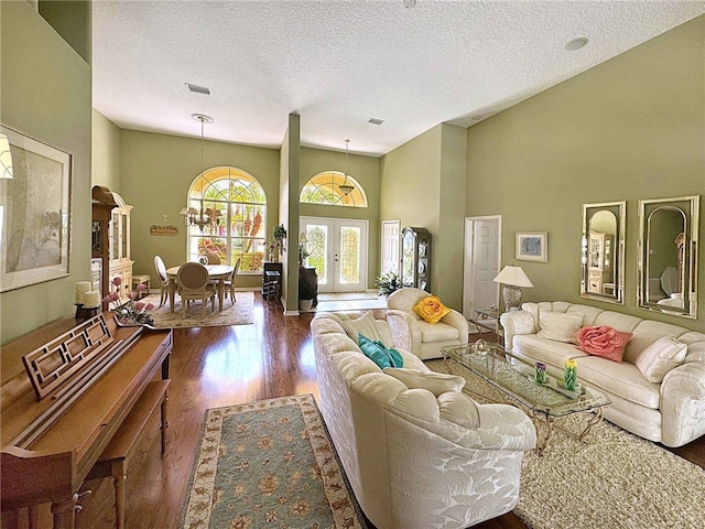 living room with hardwood / wood-style flooring, a textured ceiling, a high ceiling, and french doors