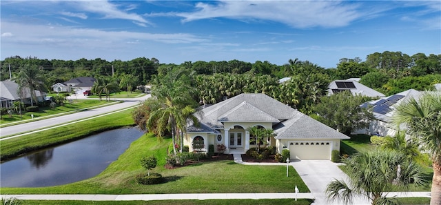 view of front of property with a water view, a front yard, and a garage