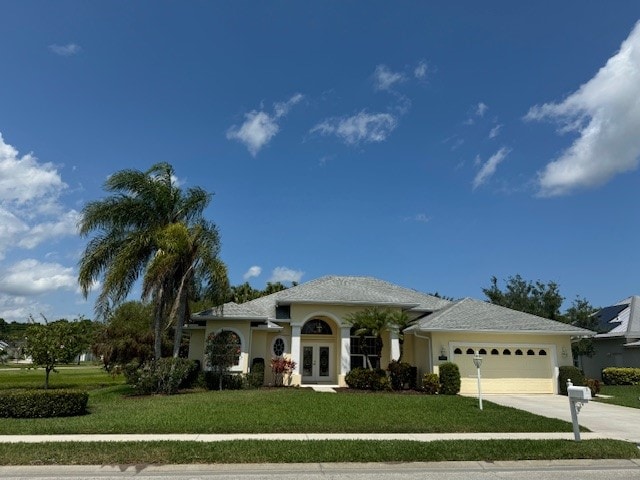 view of front of property with french doors, a front yard, and a garage