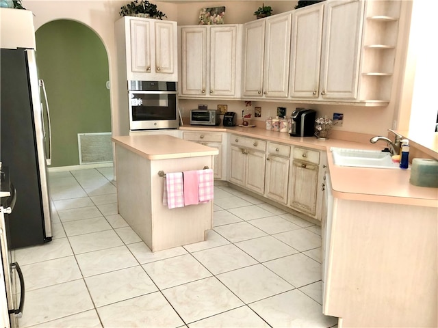 kitchen with sink, appliances with stainless steel finishes, a center island, and light tile patterned flooring