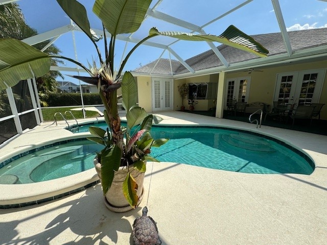 view of pool featuring glass enclosure, an in ground hot tub, a patio, and french doors