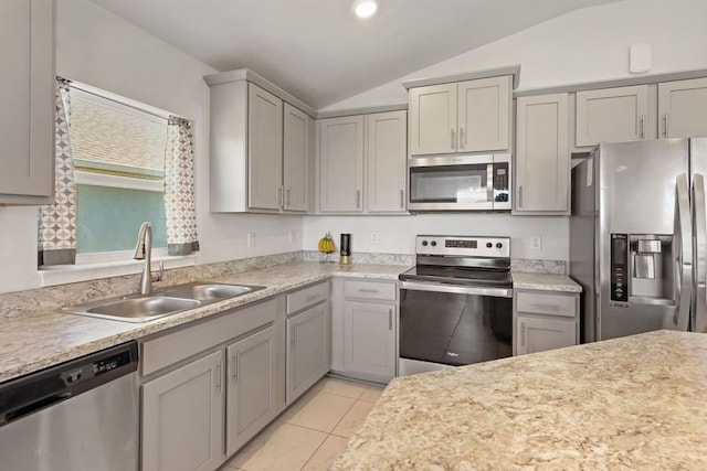 kitchen with sink, light tile patterned floors, vaulted ceiling, and appliances with stainless steel finishes