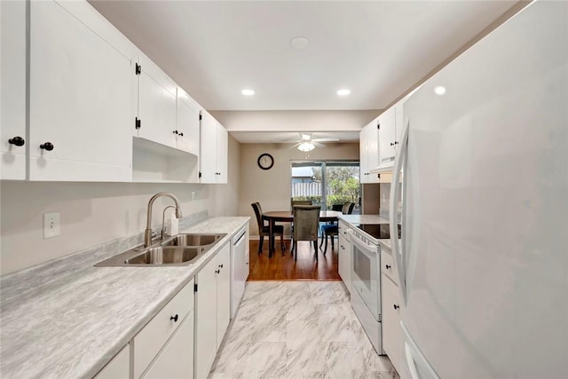 kitchen featuring white appliances, white cabinets, marble finish floor, light countertops, and a sink