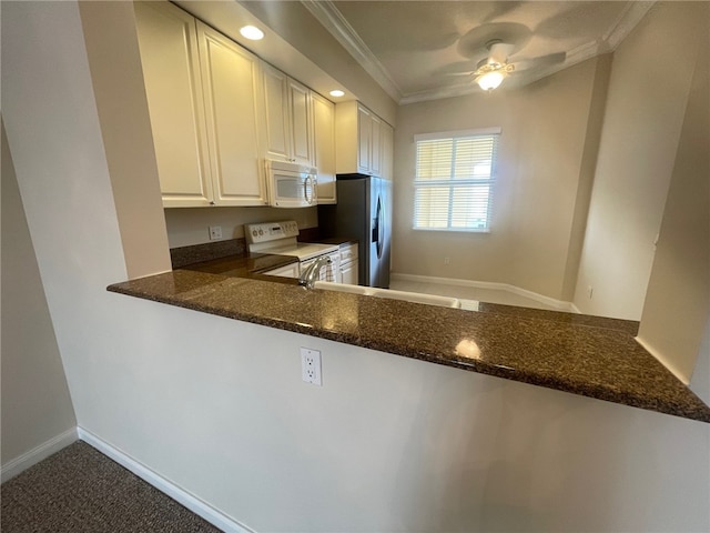 kitchen with white cabinets, kitchen peninsula, dark stone counters, and white appliances