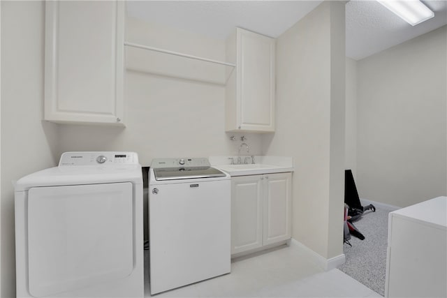 clothes washing area with cabinets, washer and dryer, a textured ceiling, and sink