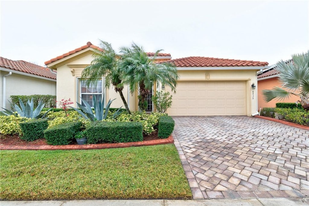 mediterranean / spanish home featuring a garage and a front lawn