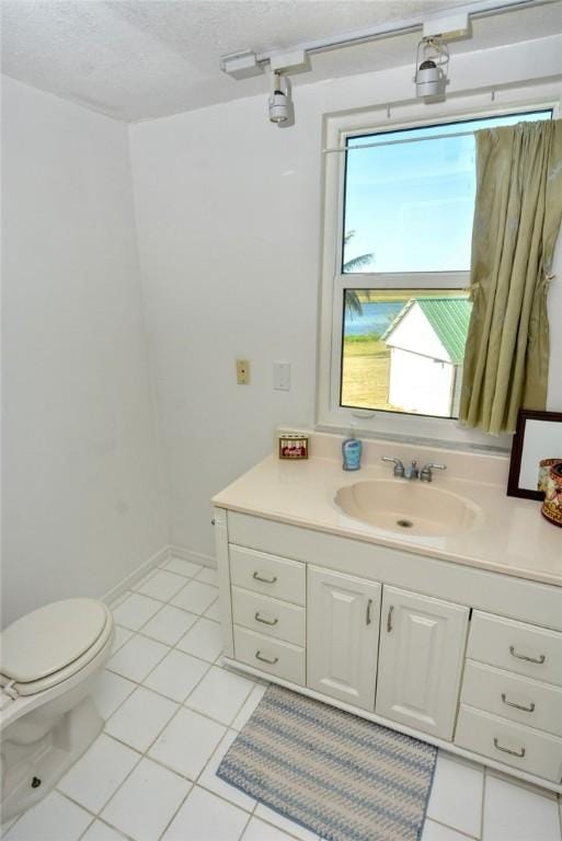 bathroom with tile patterned floors, vanity, a textured ceiling, and toilet