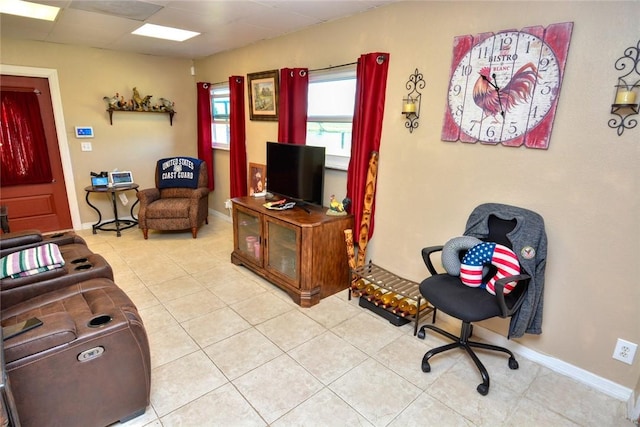 living room featuring a drop ceiling and light tile patterned floors