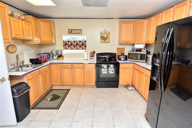 kitchen with sink, light tile patterned floors, black appliances, and light brown cabinets