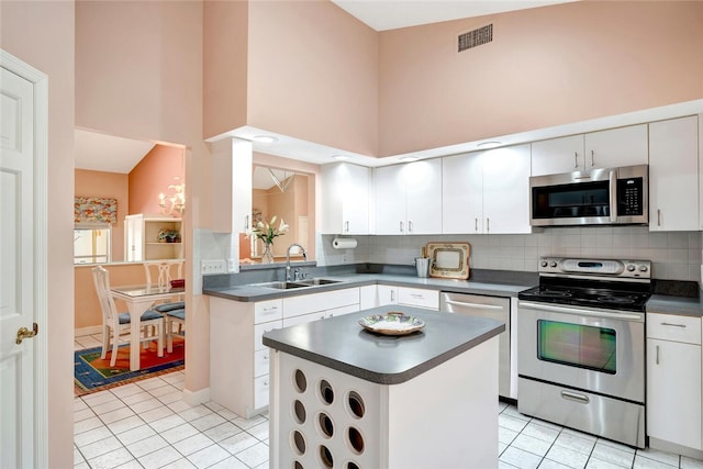 202 N Carmel Ct, Vero Beach, FL 32963 - kitchen with a sink, appliances with stainless steel finishes, dark countertops, light tile patterned flooring, and a high ceiling