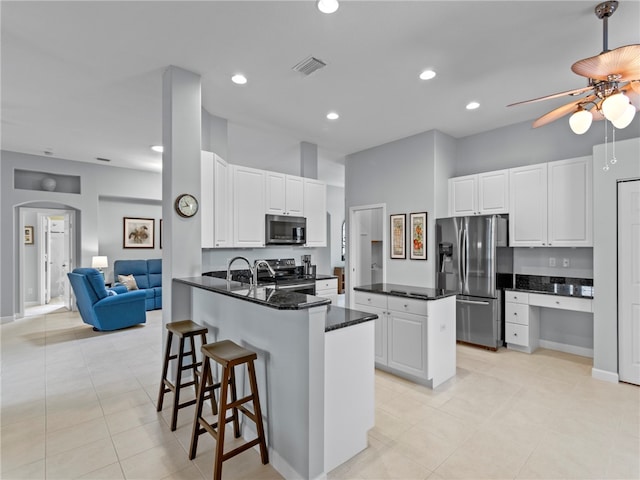 kitchen featuring white cabinetry, appliances with stainless steel finishes, light tile patterned flooring, and kitchen peninsula