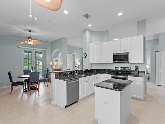 kitchen featuring white cabinets, kitchen peninsula, appliances with stainless steel finishes, and a kitchen island