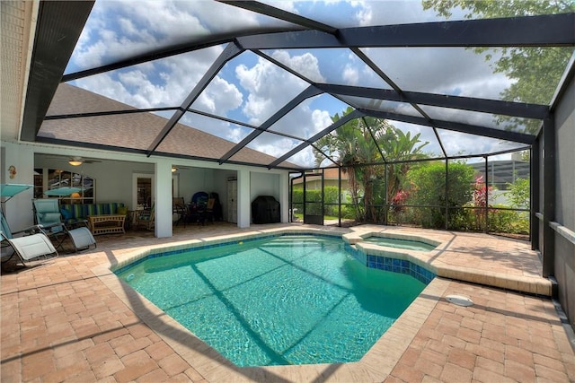 view of swimming pool featuring a patio, a pool with connected hot tub, a ceiling fan, and a lanai
