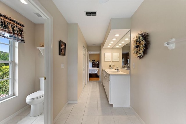 ensuite bathroom with toilet, recessed lighting, tile patterned floors, vanity, and baseboards