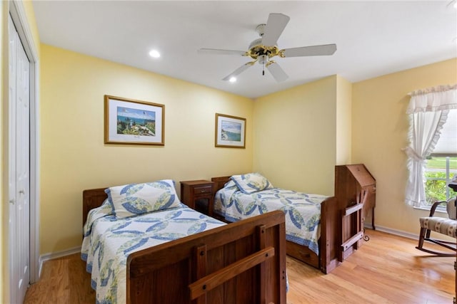 bedroom with light wood-style flooring, ceiling fan, baseboards, and a closet