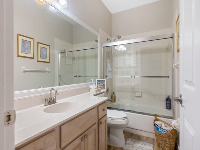 full bathroom featuring shower / bath combination with glass door, hardwood / wood-style flooring, vanity, and toilet