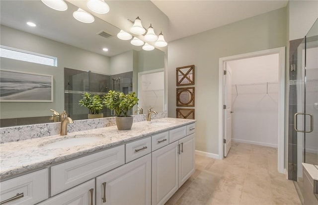 bathroom with double vanity, visible vents, a stall shower, a sink, and a spacious closet