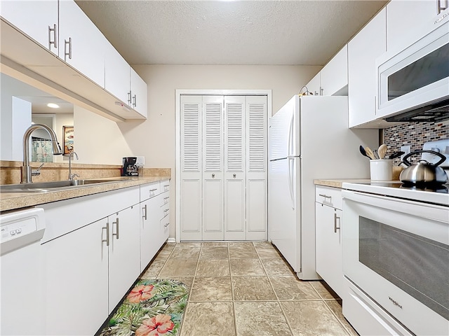 kitchen with white appliances, white cabinets, sink, a textured ceiling, and tasteful backsplash